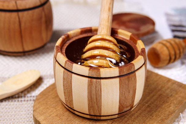 houten stok om te bowlen met vloeibare bloemen verse honing. Gezonde biologische honing druipen, gieten van honing houten lepel. - Foto, afbeelding