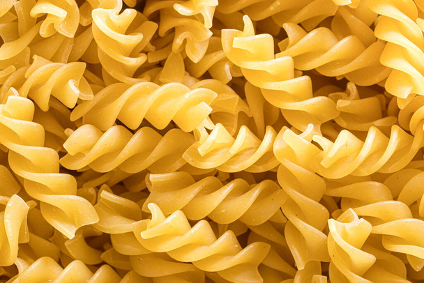 Bovenaanzicht van Italiaanse ongekookte fusilli pasta. Voedseltextuur. - Foto, afbeelding