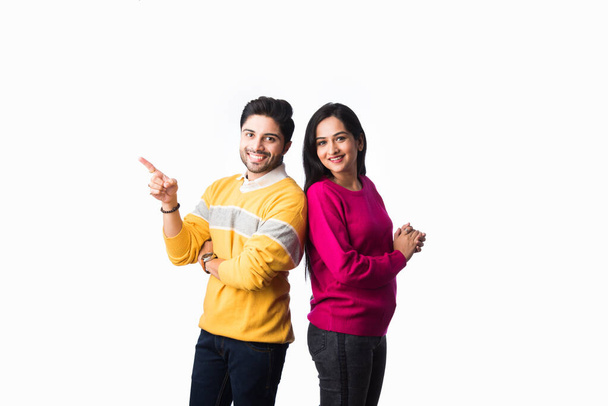 Asian Indian couple wears colourful warm sweater or woolen winter cloths, standing isolated against white background - Fotó, kép