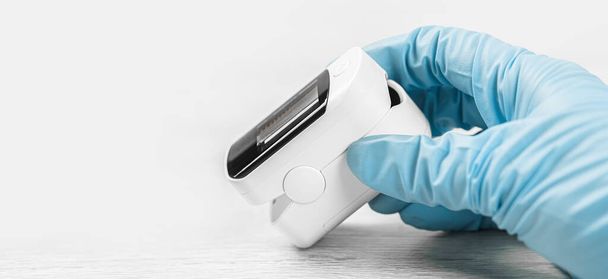 Medical concept. pulse oximeter in hand. Medical protective glove. Pneumonia, covid prevention and cure, flu sesion lockdown. Finger Oxygen meter. Viral infection respiratory disease protection banner - Photo, Image