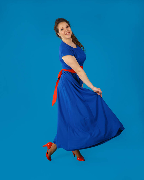 Dancing young woman in a blue dress and red shoes. - Fotoğraf, Görsel