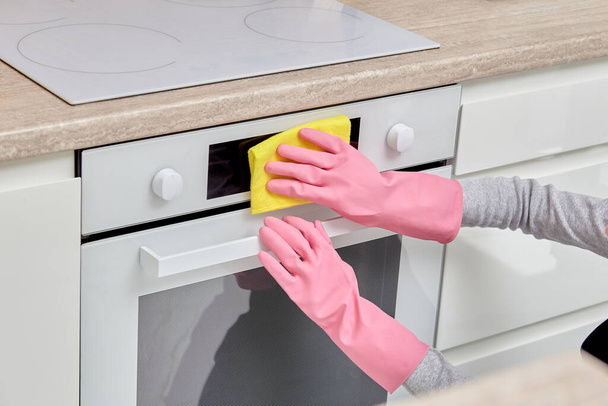 Womens hands in rubber gloves with a rag doing cleaning in the kitchen. - Foto, Imagem