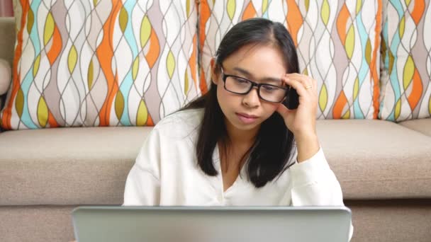 Düşünceli kadın kafaya dokunuyor ve dizüstü bilgisayara bakıyor, fikirler ve görevler üzerinde kafa yoruyor, ev ofisinde oturuyor. Coronavirus salgını sırasında evden çalışma kavramı. - Video, Çekim