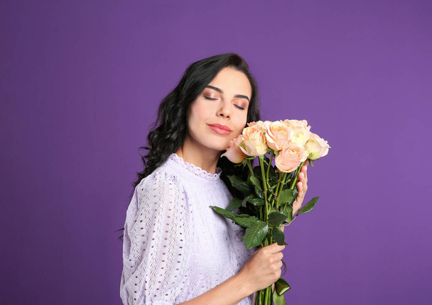 Young woman with beautiful bouquet on purple background - 写真・画像