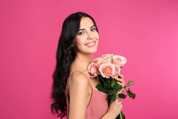 Portrait of smiling woman with beautiful bouquet on pink background - Fotoğraf, Görsel