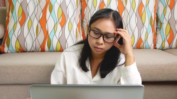 Femme réfléchie touchant la tête et regardant dans un ordinateur portable, réfléchissant à des idées ou des tâches, assis au bureau à la maison. Concept de travail à domicile pendant la pandémie de coronavirus. - Séquence, vidéo