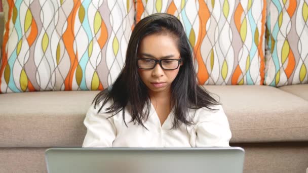 眼鏡をかけた白いシャツの深刻な女性は、自宅でノートパソコンの残業に取り組んで、ストレスから頭痛を持っています。コロナウイルス発生中の自宅からの仕事の概念. - 映像、動画