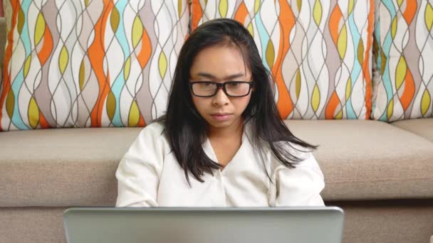 Una mujer seria con camisa blanca que lleva gafas, tiene dolor de cabeza por el estrés, trabajando en una computadora portátil horas extras en casa. Concepto de trabajo desde casa durante el brote de coronavirus. - Metraje, vídeo