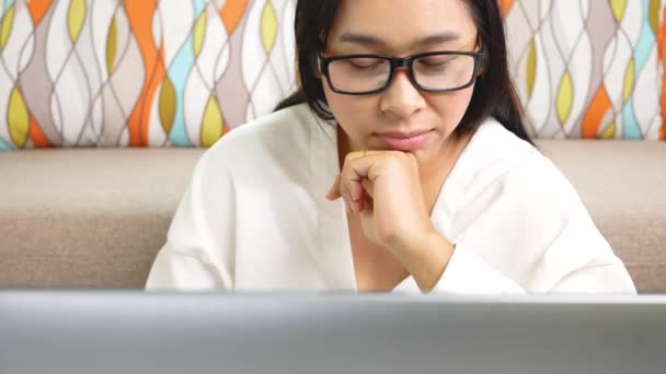 Przemyślana kobieta dotykająca podbródka i patrząca w laptopie, zastanawiająca się nad pomysłami czy zadaniami, siedząca w biurze. Koncepcja pracy w domu podczas pandemii koronawirusowej. - Materiał filmowy, wideo