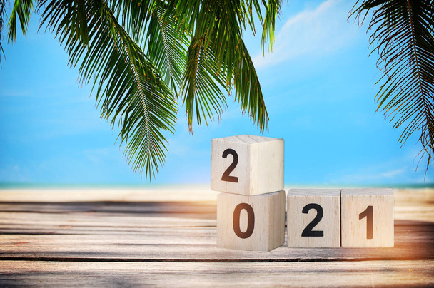Holzwürfel-Nummer 2021 auf Planken vor tropischem Strandhintergrund, Frohes Neues Jahr-Konzept und Sommerferienidee - Foto, Bild