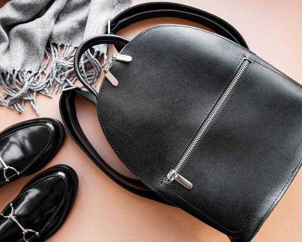 Женский черный кожаный рюкзак, обувь и шарф. Женская кожаная мода аксессуары. Квартира лежала, вид сверху. Осенняя мода в черном цвете - Фото, изображение
