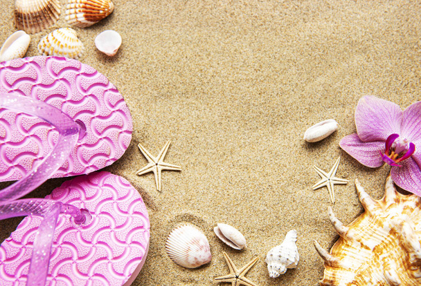 Flip Flops a homokban a tengeri csillag és orchidea virágok. Nyáron a tengerparton. Nyári strand. - Fotó, kép