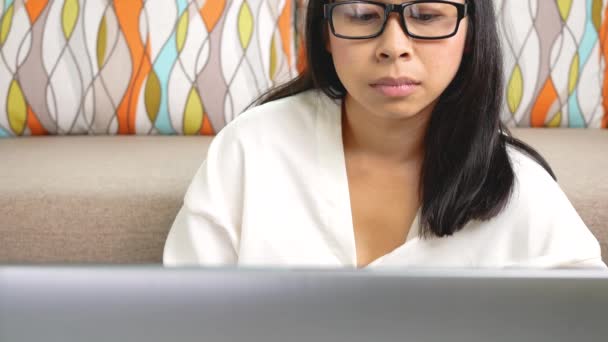 Eine junge Frau mit Brille arbeitet im Home Office an einem Laptop. Konzept der Arbeit von zu Hause aus während der Coronavirus-Pandemie. - Filmmaterial, Video