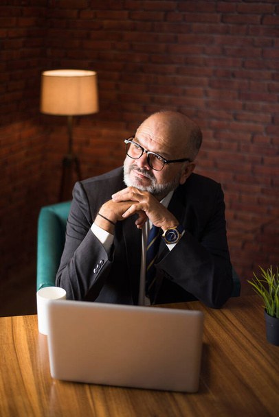 Ázsiai indiai vezető pénzügyi üzletember ül a munkaállomáson vagy íróasztal előtt egy számítógép, laptop és tabletta. Telefonon beszél, miközben papírmunkát végez. - Fotó, kép