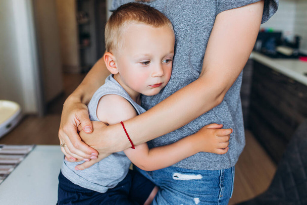 Mom hugs her son in the kitchen. Family in the kitchen. - Photo, Image