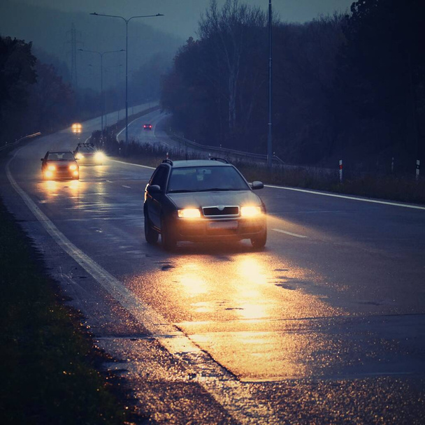 Coche en la carretera en la niebla. Paisaje otoñal: peligroso tráfico por carretera en temporada de invierno. - Foto, imagen