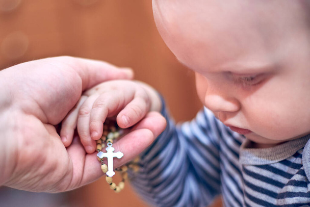 Un petit enfant prend un chapelet de la main de son père - Photo, image