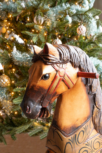 木製のヴィンテージロッキングホースとクリスマスツリーの一部の素晴らしい詳細写真。クリスマス2020. - 写真・画像