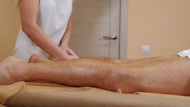 Zdravotní koncepce. Lékař provádějící ruční lymfatickou odvodňovací masáž proti celulitidě mužskému pacientovi ležícímu na masážním stole. Profesionální masáž mužských nohou. 4 k video - Záběry, video