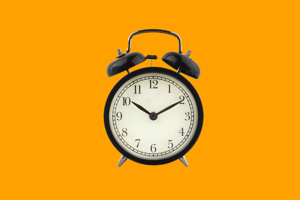 オレンジ色の背景に目覚まし時計。ビジネスとコピースペースのコンセプト - 写真・画像