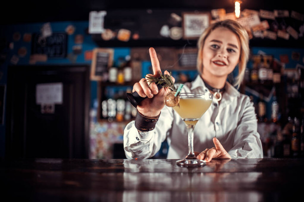 Chica barman profesional demuestra sus habilidades profesionales mientras está de pie cerca del mostrador de bar en el bar - Foto, imagen