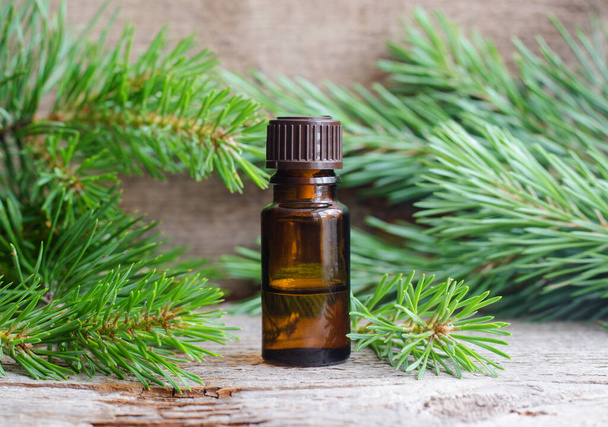 Small bottle with essential pine oil (extract, tincture, infusion). Old wooden background. Aromatherapy, spa and herbal medicine concept. Copy space.  - Photo, Image