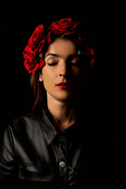Молода жінка з закритими очима в вінку з квітами на чорному тлі
 - Фото, зображення