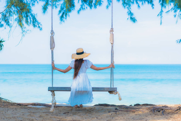 Portrait beautiful young asian woman relax smile leisure on swing around beach sea ocean with blue sky white cloud - Foto, afbeelding