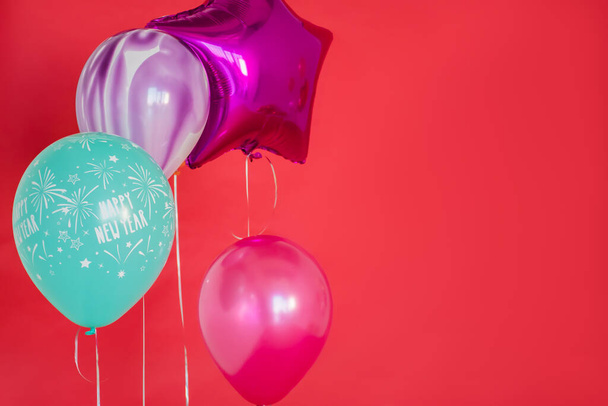 Πολύχρωμα μπαλόνια με κόκκινο φόντο στο πρωτοχρονιάτικο πάρτι. - Φωτογραφία, εικόνα