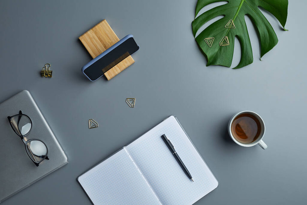 Minimal above view flat lay of tropical leaf and business accessories over grey workplace background, copy space - Фото, зображення