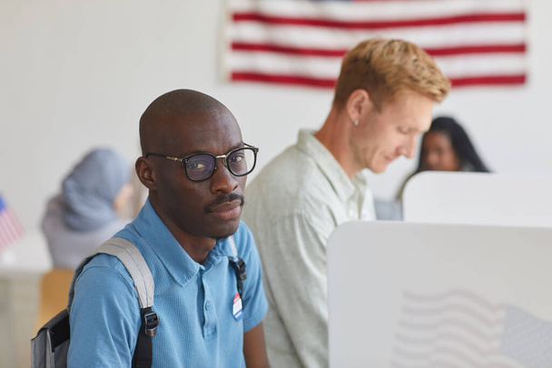 選挙の日に投票ブースに立っている間に離れて見て現代アフリカ系アメリカ人の男の高い角度の肖像画、スペースをコピー - 写真・画像