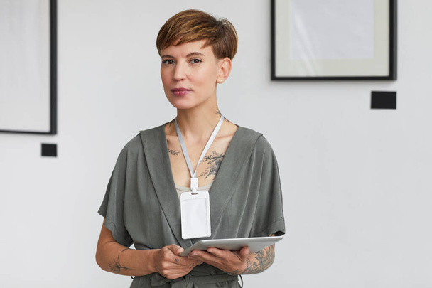 Taille omhoog portret van creatieve getatoeëerde vrouw kijken naar de camera tijdens het plannen van kunstgalerie tentoonstelling, kopieer ruimte - Foto, afbeelding