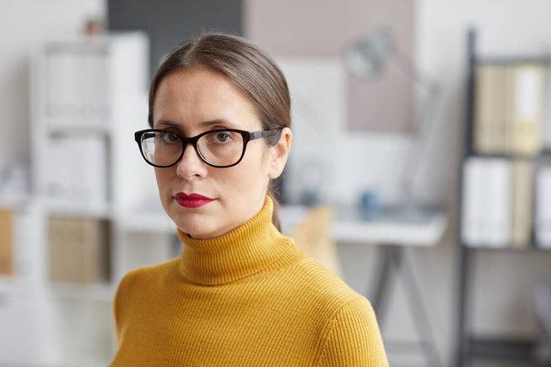 Close up portrait of adult woman wearing glasses and looking at camera while standing in architects office, copy space - Photo, Image