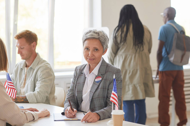 Πορτρέτο της σύγχρονης ώριμης γυναίκας εγγραφή ψηφοφόρων, ενώ εργάζονται στο γραφείο την ημέρα των εκλογών, αντιγραφή χώρου - Φωτογραφία, εικόνα