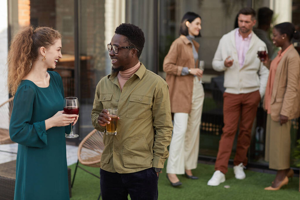 Grupo multi-étnico de pessoas adultas contemporâneas conversando enquanto desfruta de festa ao ar livre no terraço, espaço de cópia - Foto, Imagem
