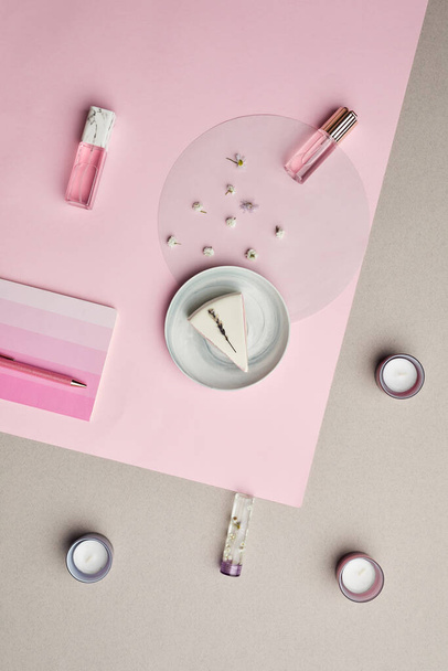 Composición mínima de frascos de perfume y pastel sobre fondo gráfico rosa, espacio para copiar - Foto, imagen