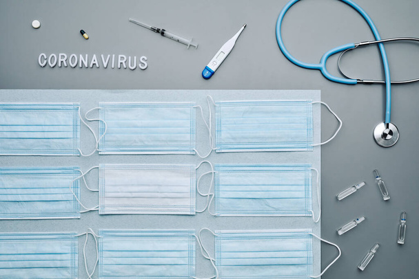Orvosi maszkok minimális grafikai összetétele sztetoszkóppal és koronavírus szóval, szürke háttérrel, másolás - Fotó, kép