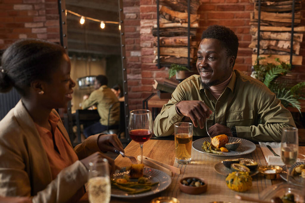 Портрет молодого афро-американського чоловіка, який посміхається в дівчини під час вечері. - Фото, зображення