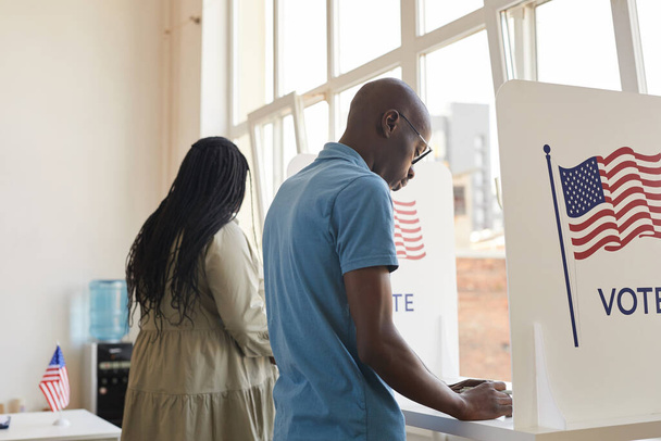 Rückseite Porträt junger Afroamerikaner, die in der Wahlkabine stehen und denken, Kopierraum - Foto, Bild