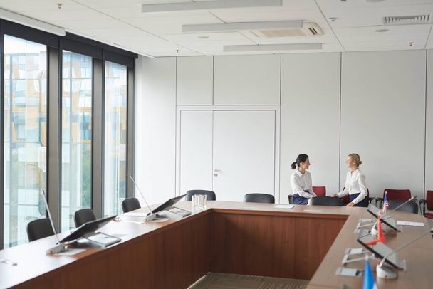 Širokoúhlý záběr klasického interiéru konferenční místnosti se dvěma sekretářkami v pozadí, kopírovací prostor - Fotografie, Obrázek