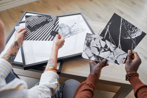 High angle close up of two modern young people discussing black and white pictures while choosing artwork for interior decor, copy space - Photo, Image