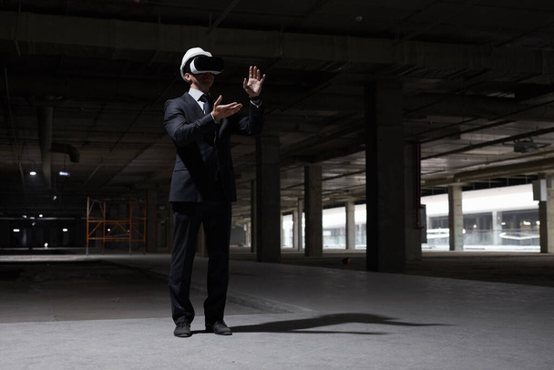 Dramatische portret van een zakenman in VR-uitrusting op de bouwplaats, terwijl het visualiseren van toekomstige project in 3D, kopieer ruimte - Foto, afbeelding