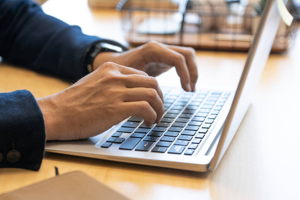Dłonie młodego współczesnego menedżera biura męskiego nad klawiszami klawiatury laptopa przeglądającego się w sieci siedząc przy pracy w biurze - Zdjęcie, obraz