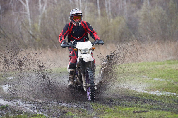 Motociclista corse in zona rurale mentre schizza acqua sporca - Foto, immagini