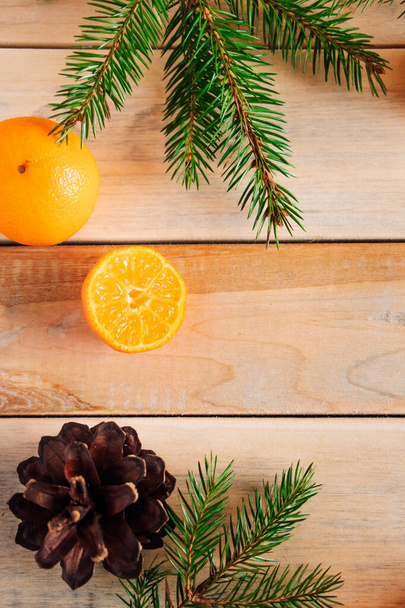 Christmas decor. Fir branches, cones and tangerines on a wooden background. - Foto, imagen