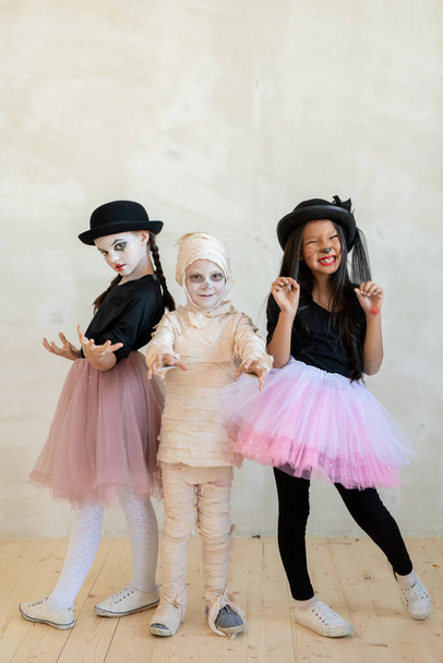 Портрет емоційних багатоетнічних дітей в костюмах мімів і матусі роблять страшні жести на Хелловін вечірці. - Фото, зображення