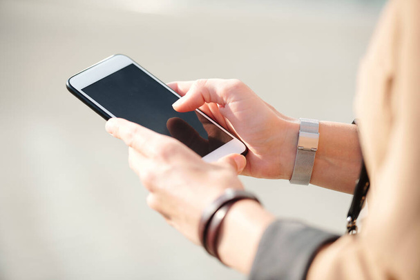 Χέρια των νέων κομψό επιχειρηματίας με smartphone κύλιση μέσω επαφών, ενώ πρόκειται να τηλέφωνο έναν από τους πελάτες σε εξωτερικούς χώρους - Φωτογραφία, εικόνα