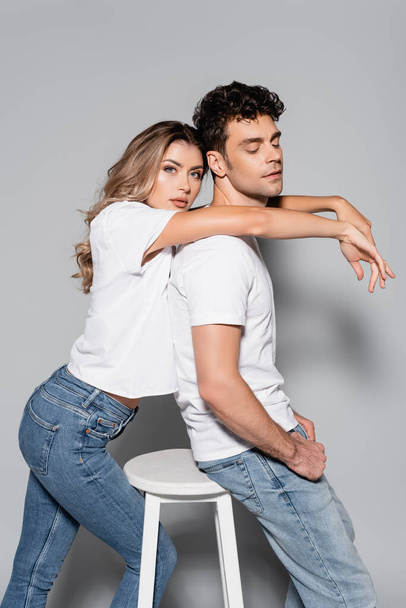 side view of young couple in white t-shirts hugging isolated on grey - Фото, зображення