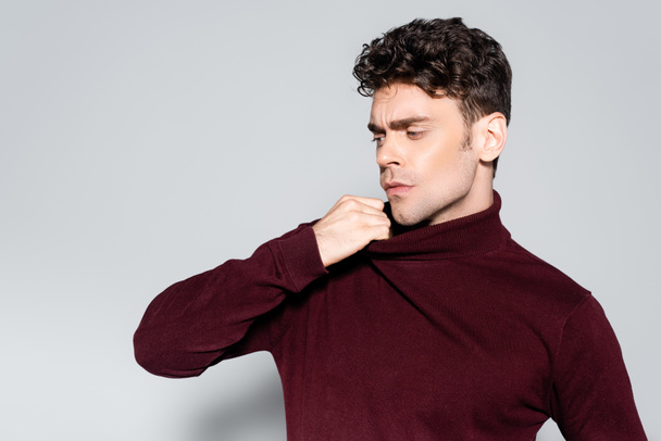 young man in burgundy turtleneck jumper posing isolated on grey - Foto, Bild