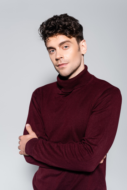 young man in burgundy turtleneck jumper posing isolated on grey - Фото, изображение